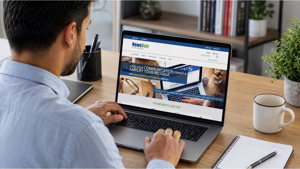 Man using a laptop displaying the NewsVoir website at a tidy workspace desk