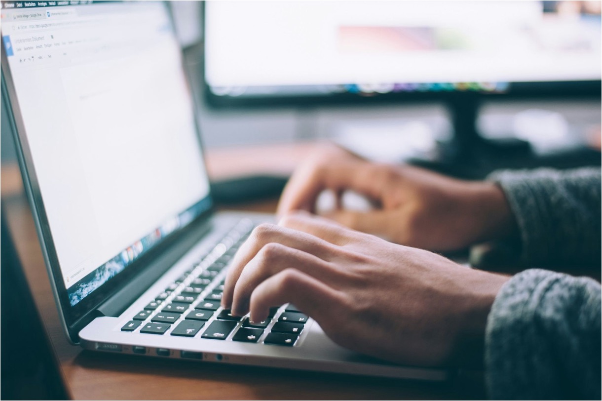 Person typing on a laptop, making a press release to be distributed