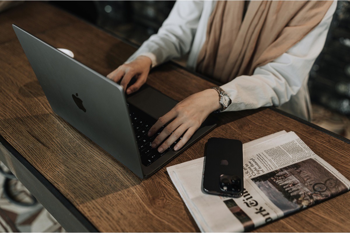 Writer drafting a press release for immediate release with a newspaper and phone nearby