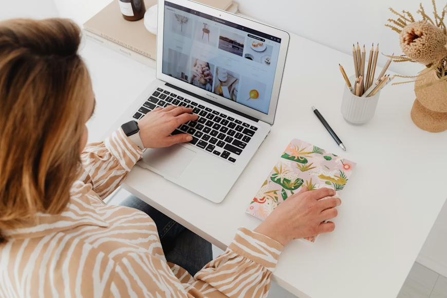 Writer reviewing image gallery on a laptop while preparing multimedia assets for a press release.