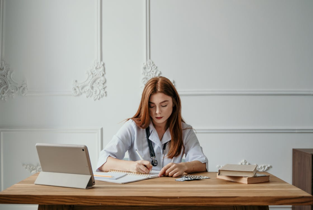 Clinician writing notes at a desk with a tablet, illustrating the careful documentation behind a telehealth press release.