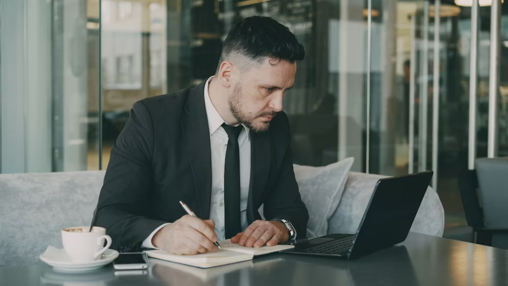 Business executive taking notes at a laptop while drafting an earnings announcement press release.