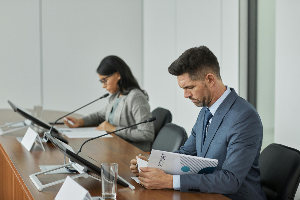 Two professionals seated at a press conference table, representing the formal presentation of case study results to the media.
