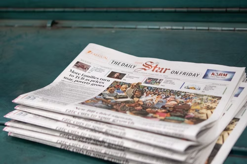 A stack of folded "The Daily Star on Friday" newspapers on a green surface.
