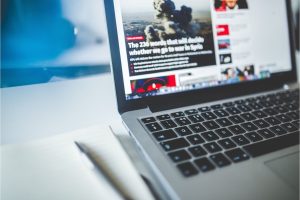 Business Wire vs PRWeb: Pros & Cons, Costs, Alternatives Laptop displaying an online news site, illustrating press release distribution through Business Wire and PRWeb